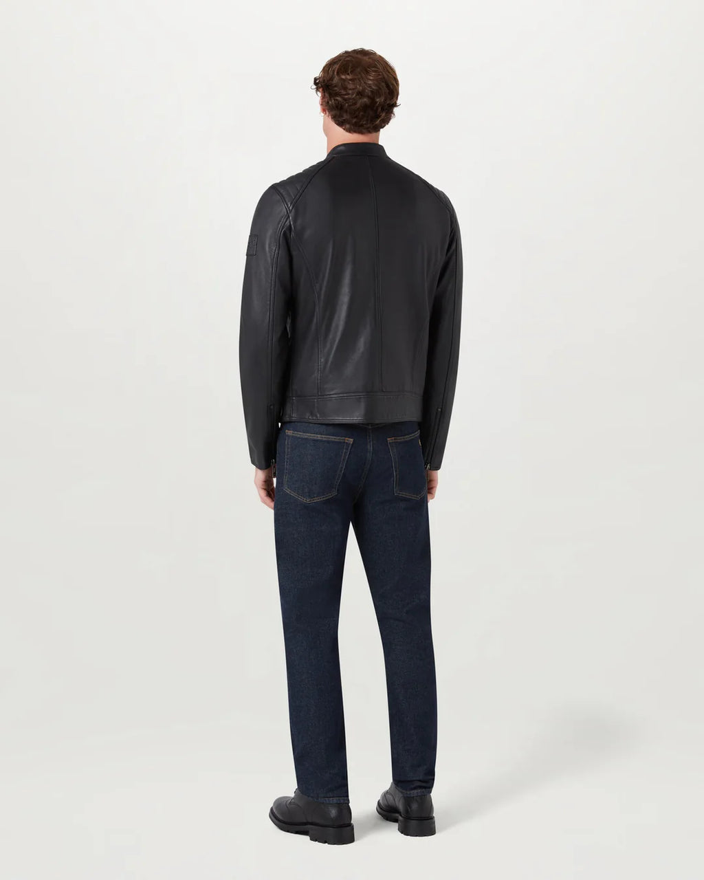 Man wearing a black jacket and dark jeans on a white background
