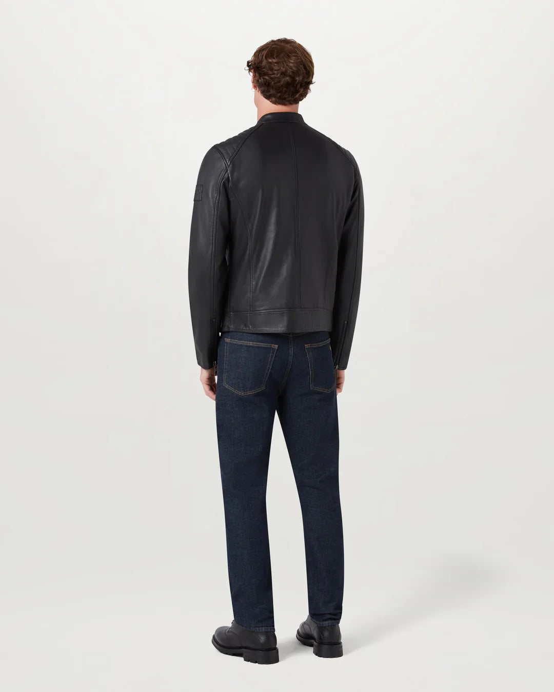 Man wearing a black jacket and dark jeans on a white background