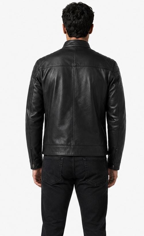 A man viewed from the back wearing a black leather jacket and black jeans against a plain white studio background.