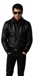 A man wearing a black leather bomber jacket, black pants, and black sunglasses, standing against a plain white background.