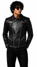 A man wearing a black leather moto jacket with silver zippers, black pants, and sunglasses, photographed against a plain white background.