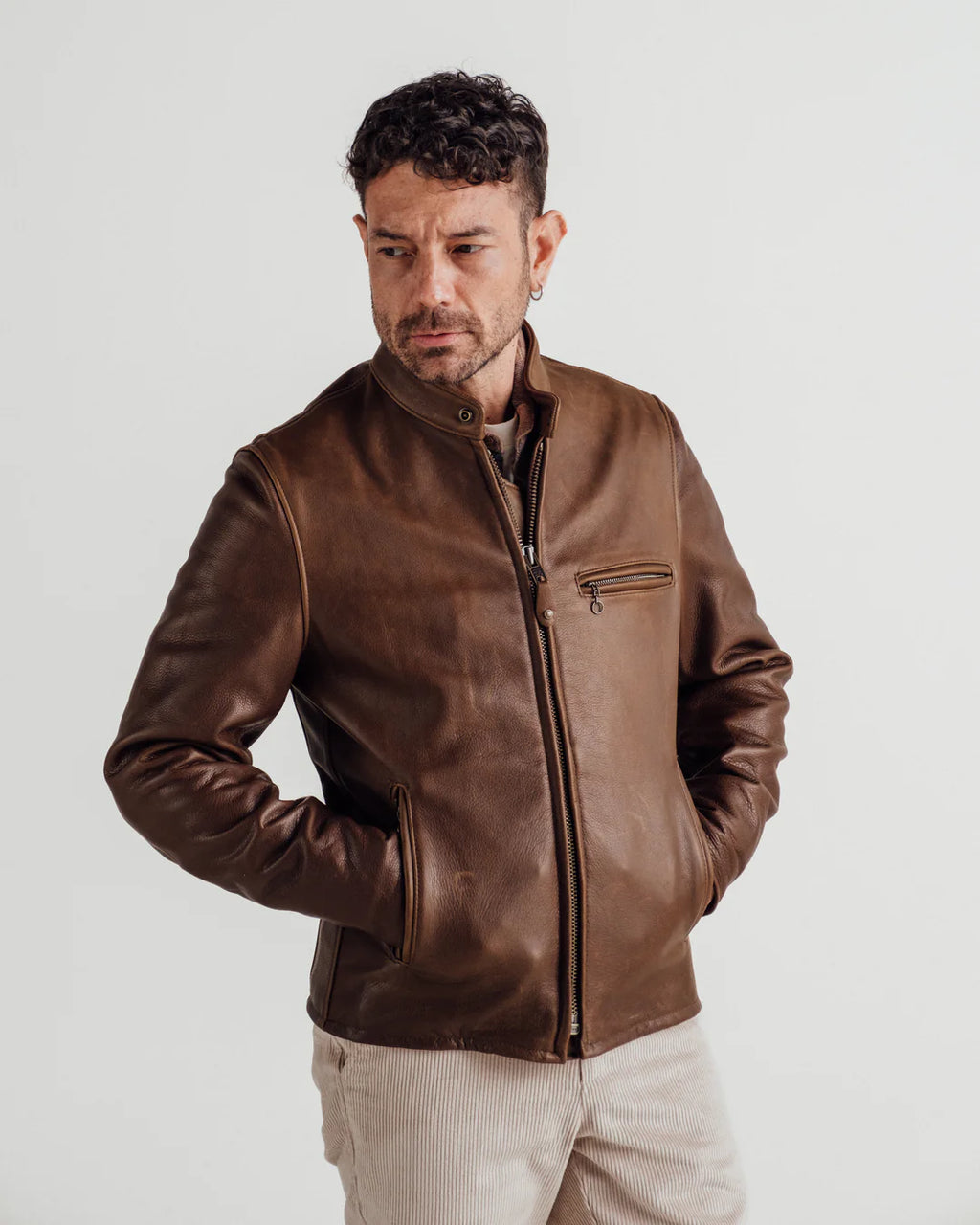 Man wearing a brown leather jacket on a plain background