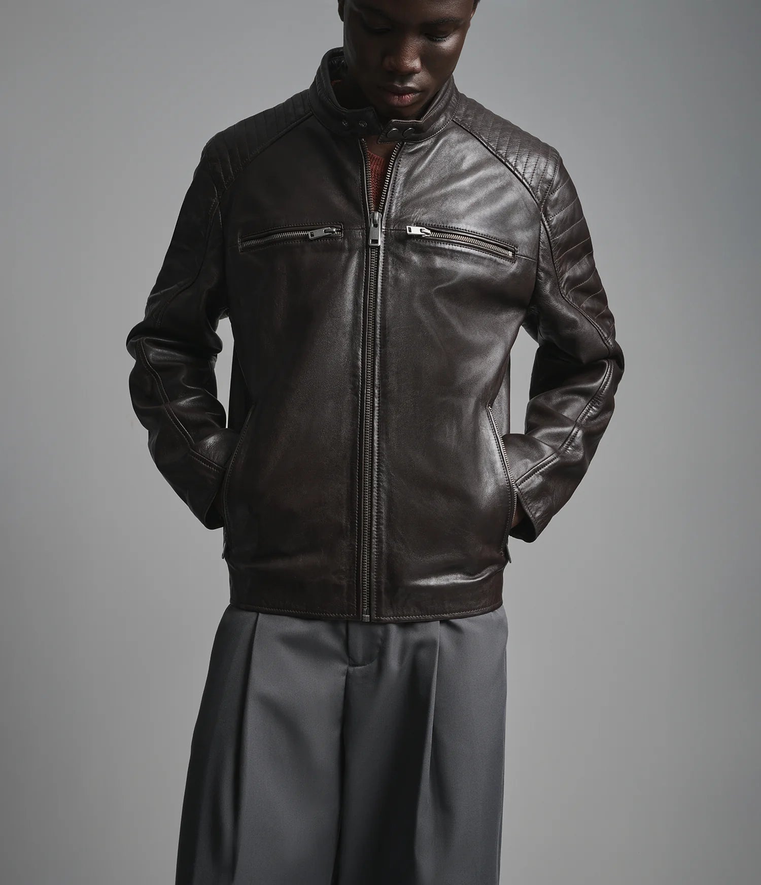 Man wearing a dark leather jacket on a gray background