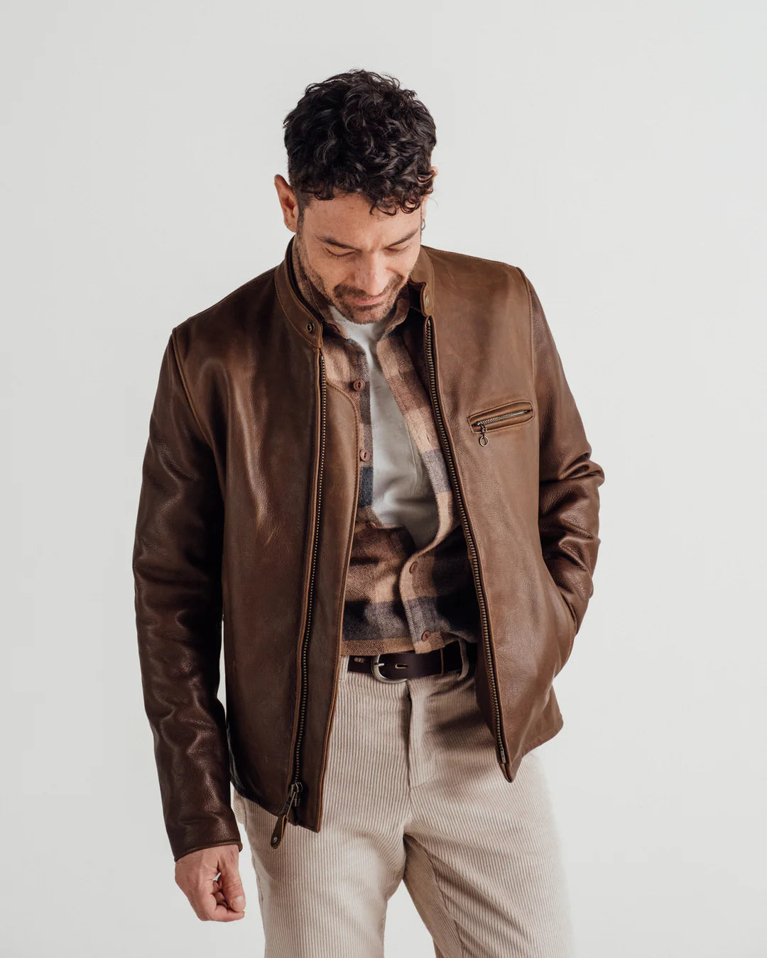 Man wearing a brown leather jacket on a plain background
